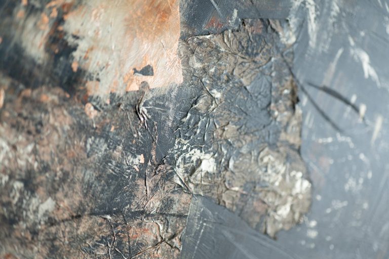 Nahaufnahme von verbranntem Material mit schwarz-grauer Textur und Faserstrukturen.